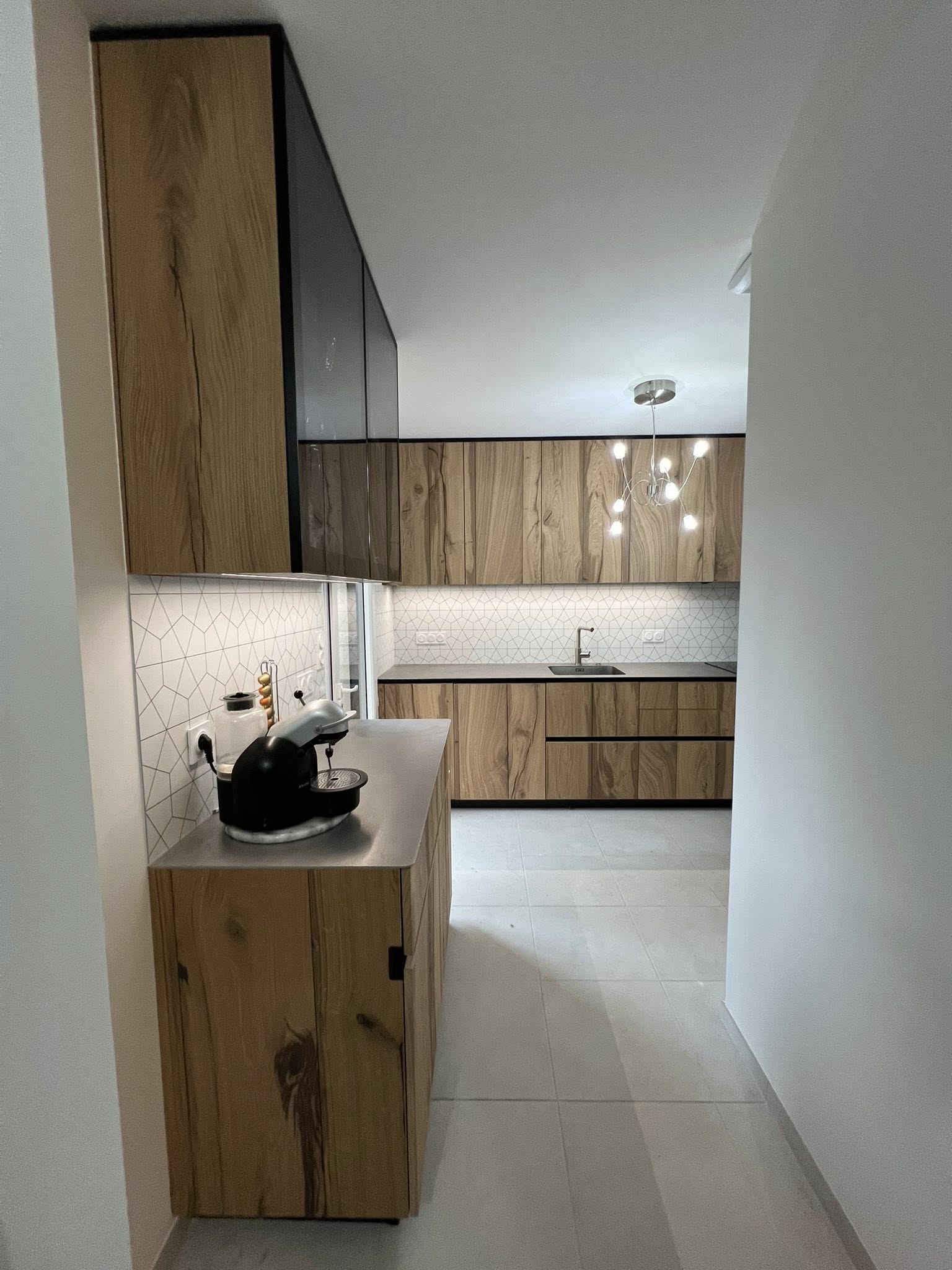 Cuisine en bois et noir avec éclairage suspendu et agencement linéaire Groizeau.