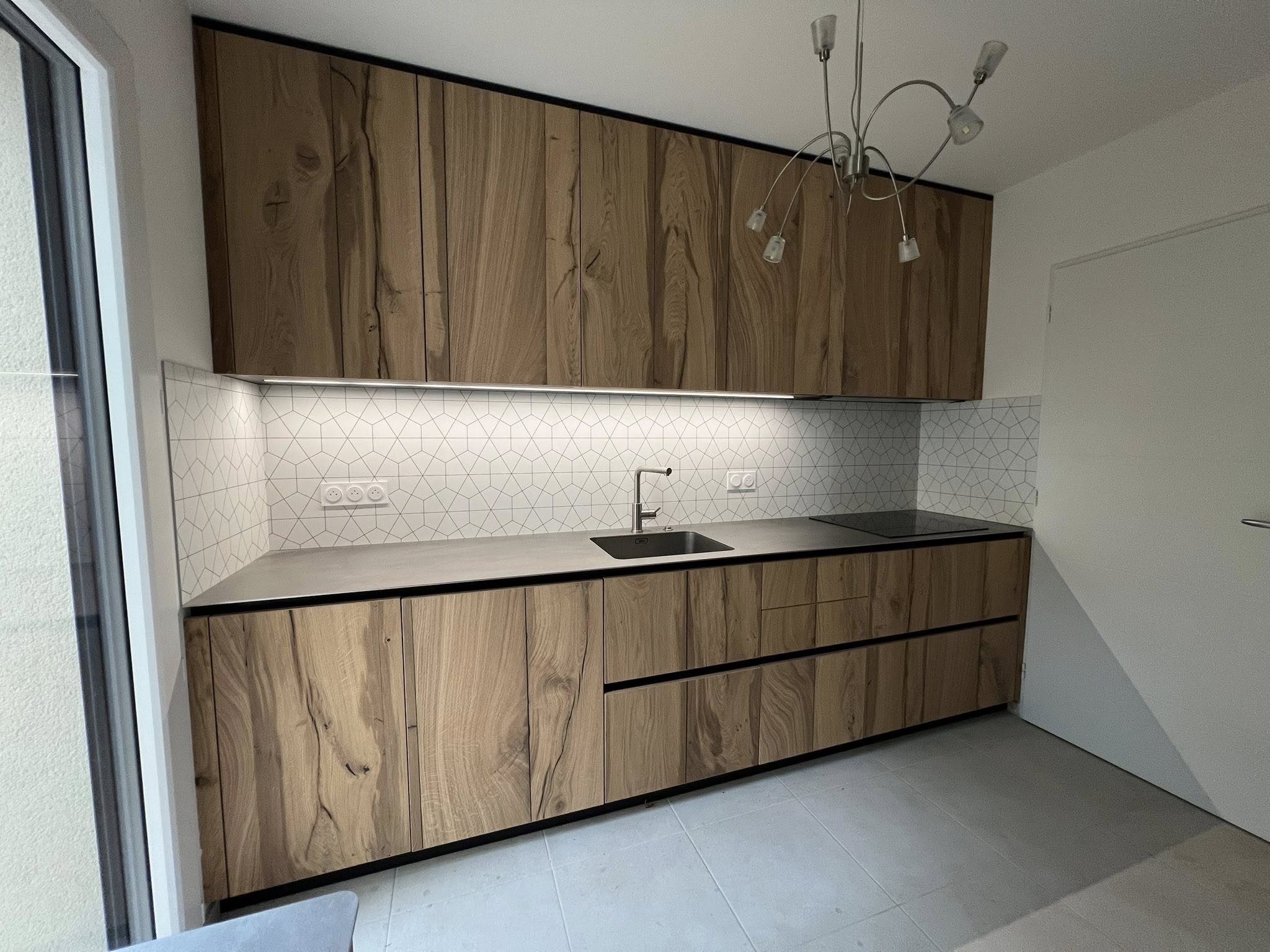 Cuisine en chêne avec poignées intégrées et crédence claire, création sur mesure Groizeau.