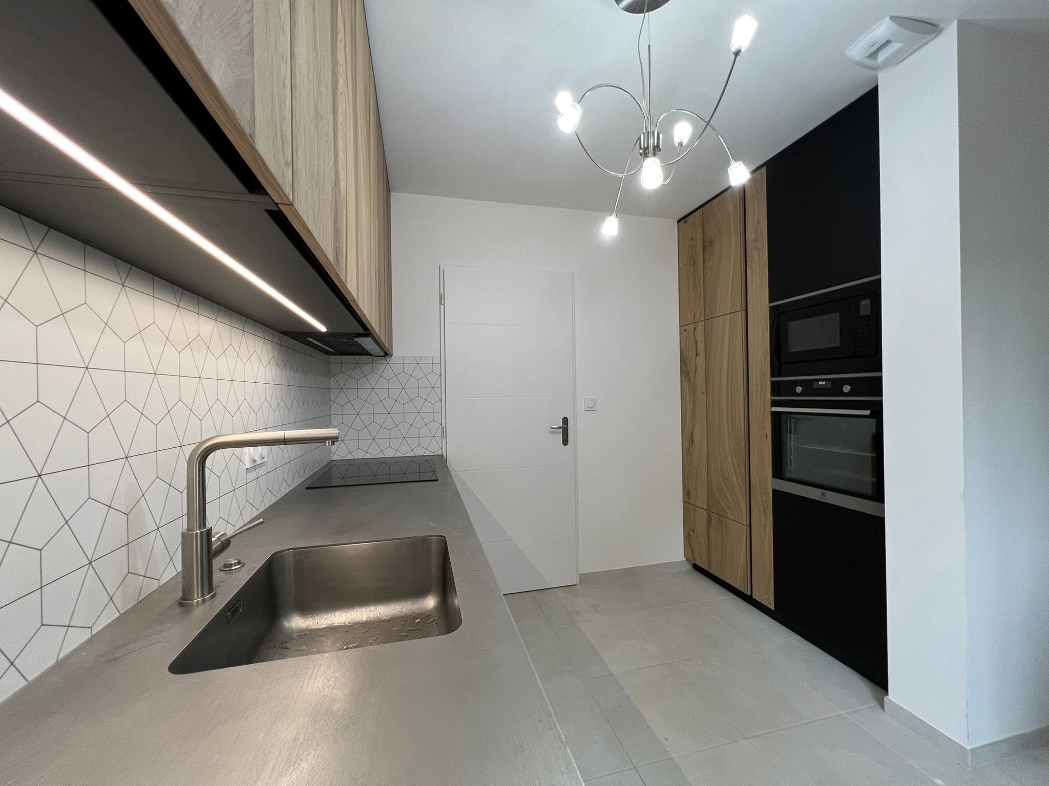 Cuisine sur mesure avec évier inox, plan de travail gris et colonnes techniques Groizeau.