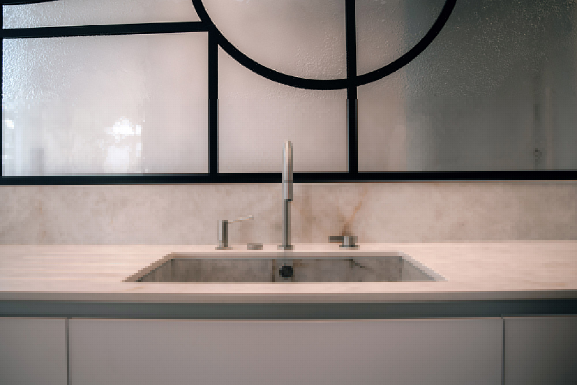 Plan de travail avec évier céramique et cloison en verre décoratif.