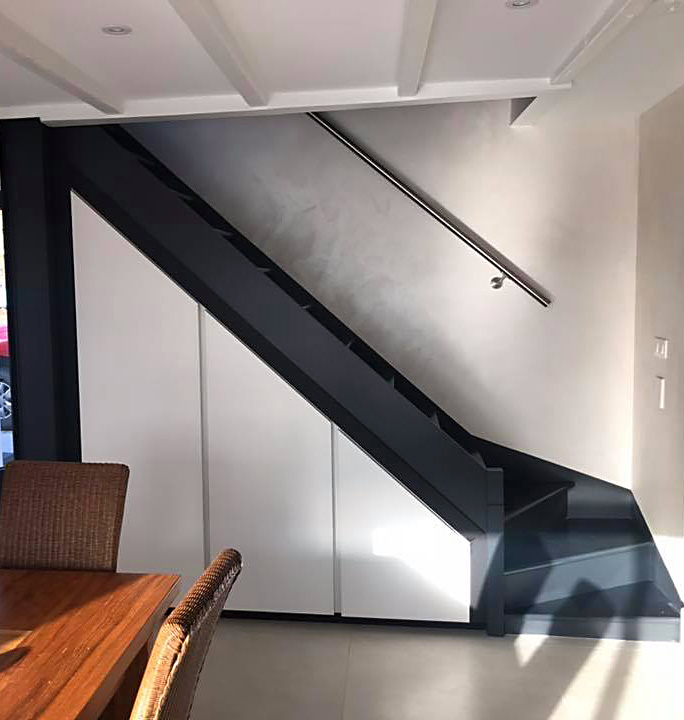 Intégration parfaite de placards blancs sous un escalier noir