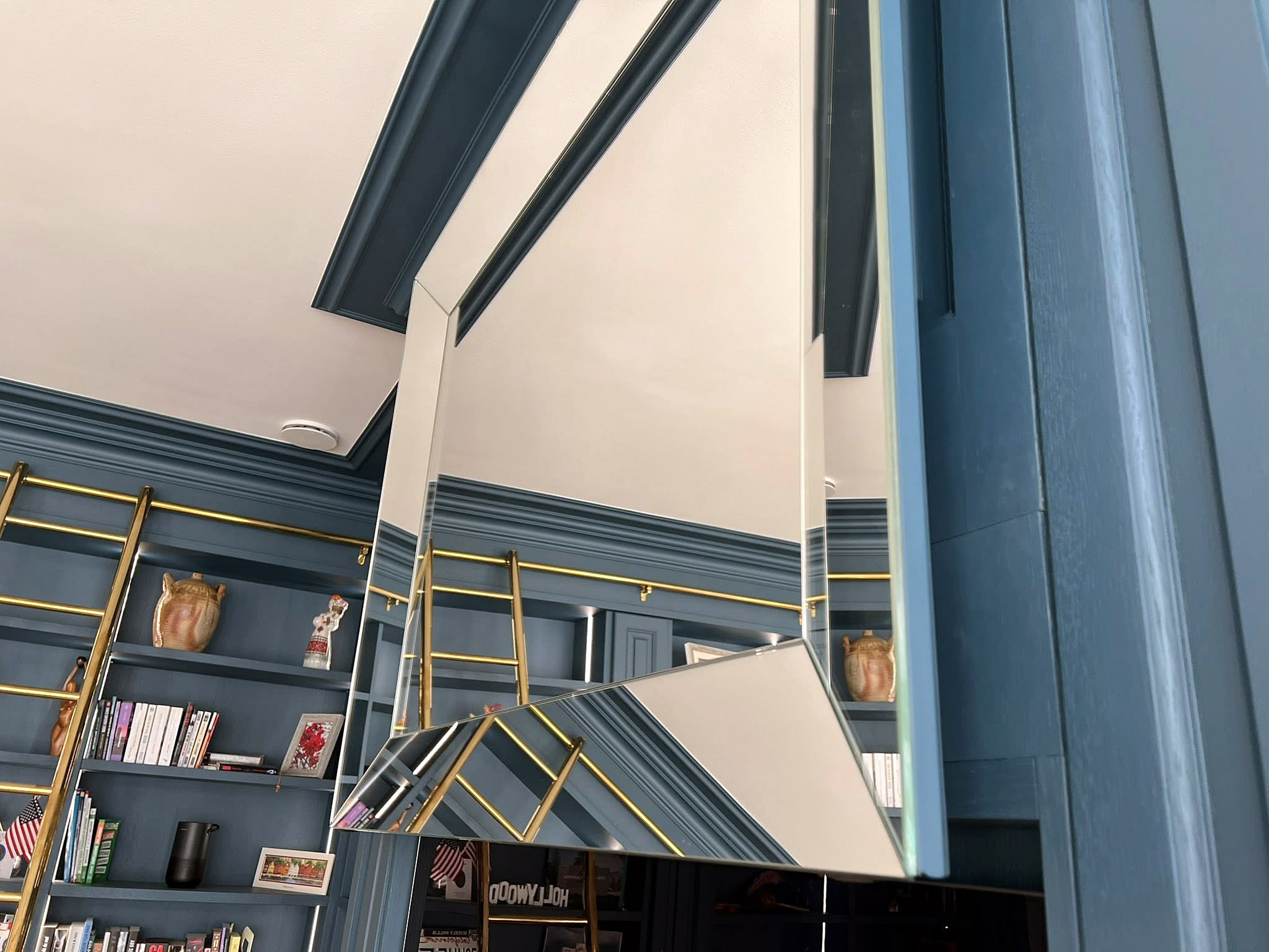 Miroir coulissant intégré dans un coffrage menuisé bleu, permettant de masquer une télévision.