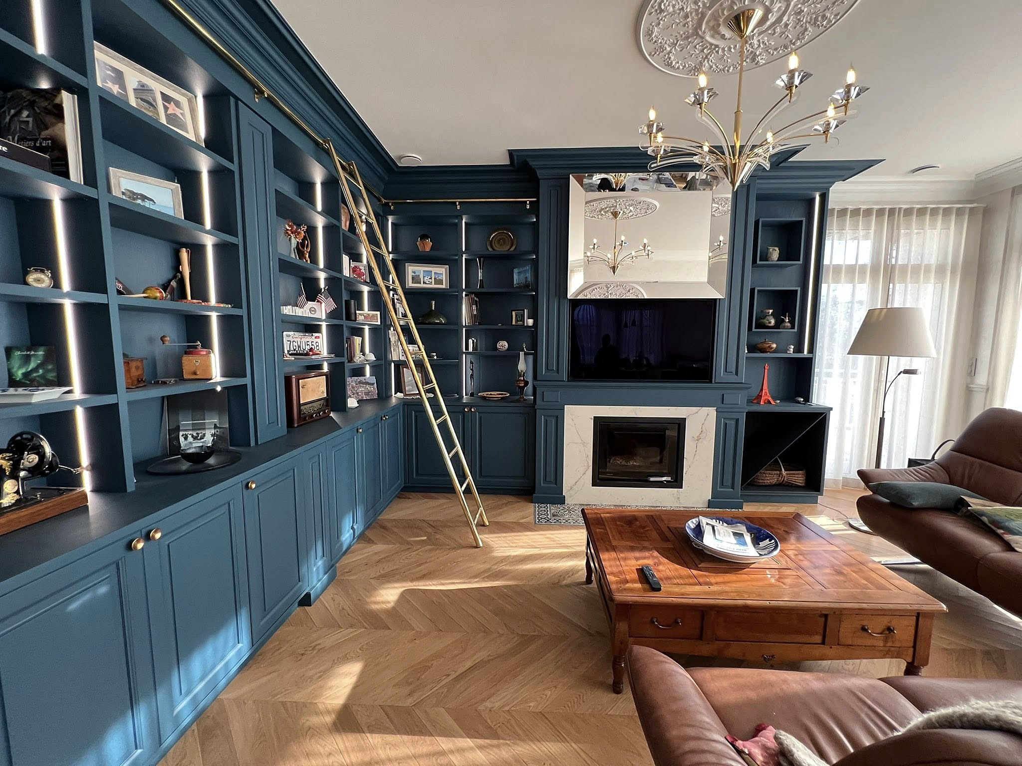 Bibliothèque haut de gamme avec échelle en laiton sur rail et éclairage intégré.