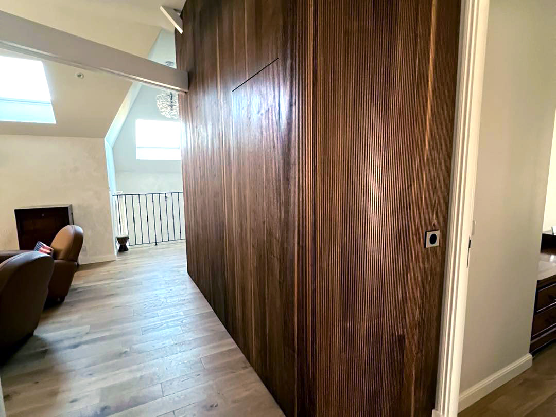 Porte dérobée dans un mur en noyer avec angle arrondi