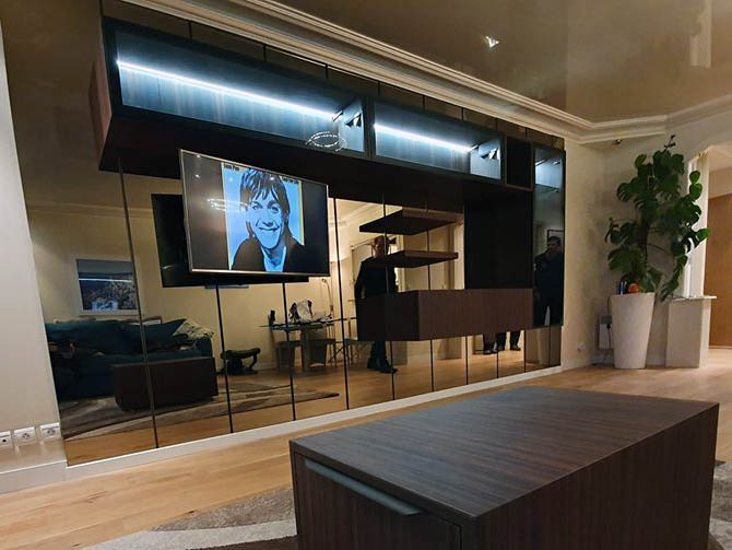 Meuble suspendu sur un ensemble de miroirs verticaux.