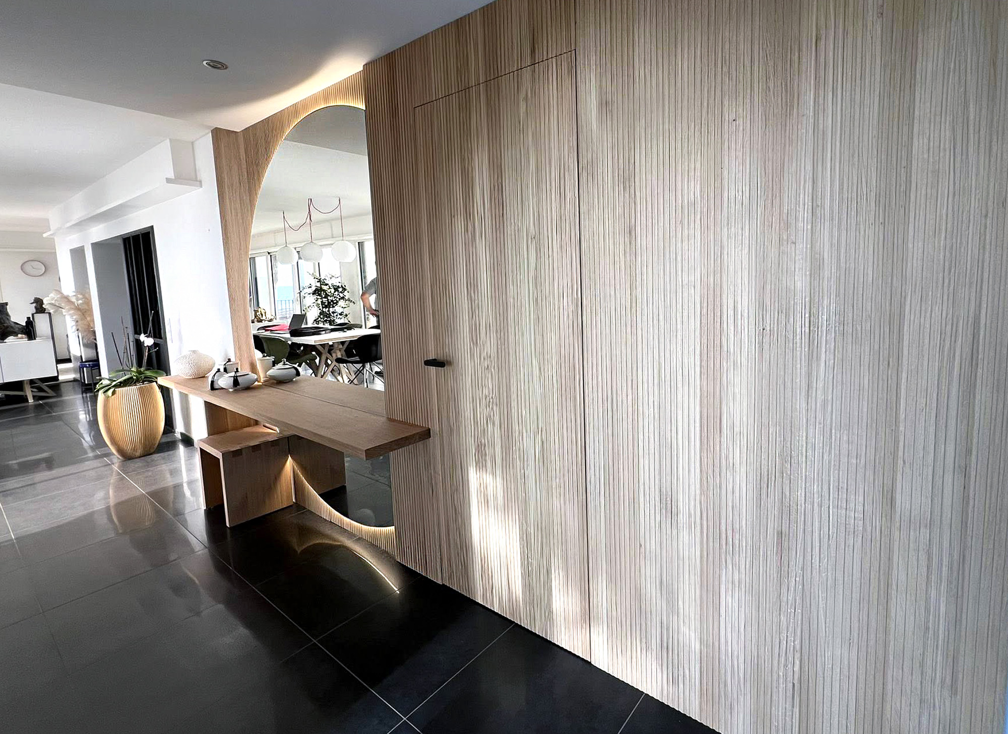 Entrée sur mesure Groizeau avec mur en chêne rainuré, porte affleurante invisible et console d'appoint avec miroir demi lune