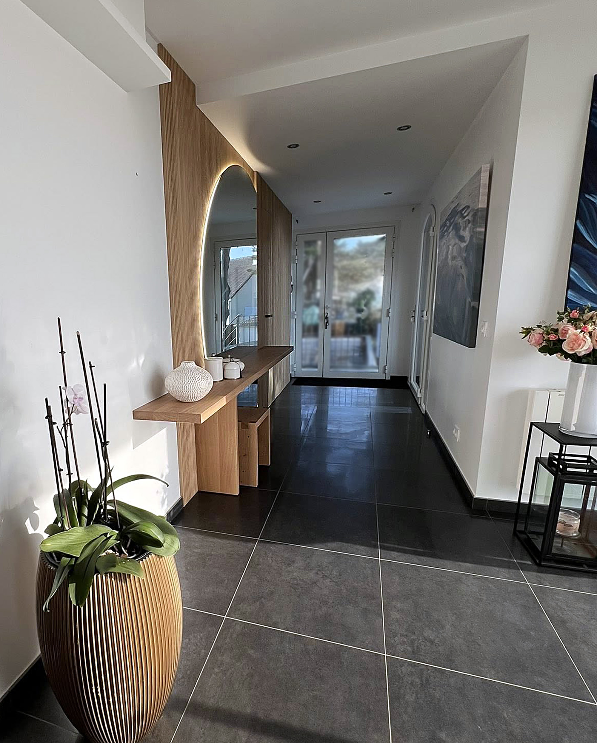 Console suspendue en chêne clair dans une entrée, avec miroir circulaire rétroéclairé et design sur mesure Groizeau