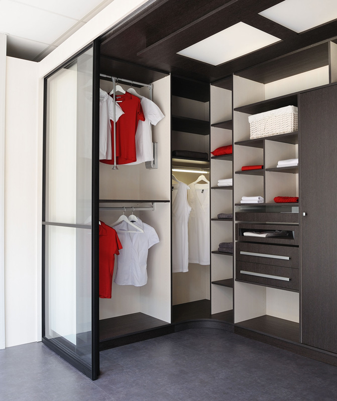 Grand dressing en U avec trois penderies tiroirs spécifiques avec vue (façade verre), l’éclairage design est assuré par des LED derrière un panneau de bois et de verre (éclairage indirecte)